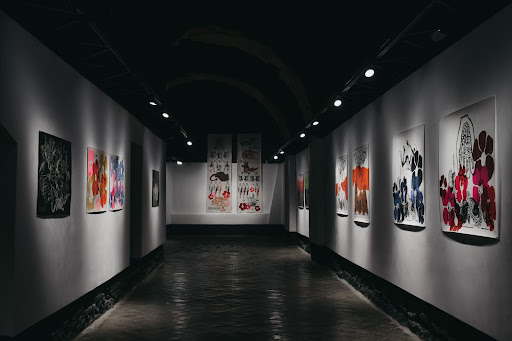 Colourful art hung in a dark hallway in an art gallery as part of an exhibition